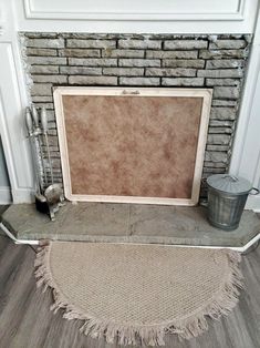 an empty fireplace with a rug and bucket on the floor