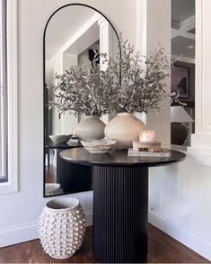 a mirror and vase on a table in a room