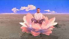 a man sitting on top of a pink flower in the middle of a desert field