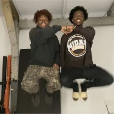 two young men standing on top of a skateboard in a garage with their arms around each other