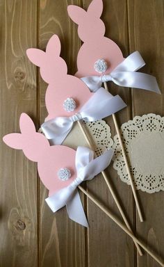 three pink and white bunny ears on sticks with lace doily next to each other