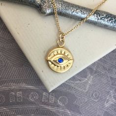 ⇩CLICK BELOW FOR DETAILS⇩Please note that I make every effort to mail your order within 24 hours of receipt. However, USPS is experiencing significant delivery delays and many packages are taking 2-3 weeks to arrive.Made of all 14kt gold filled, this beautiful evil eye necklace has a 11.5mm disc shaped evil eye charm with a tiny and bright faceted synthetic blue sapphire or red ruby center stone.  The charm is identical on both sides, and hangs a jump ring from a delicate 14kt gold filled chain, Spiritual 14k Gold Filled Tarnish-resistant Jewelry, Handmade 14k Gold Spiritual Necklace, 14k Gold Amulet Charm Necklace With Round Pendant, 14k Gold Spiritual Round Pendant Charm Necklace, Spiritual 14k Gold Charm Necklace With Round Pendant, Handmade Spiritual 14k Gold Filled Necklace, 14k Gold Filled Spiritual Necklaces, Spiritual Round Gold-plated Necklaces, Handmade 14k Gold Jewelry For Good Luck