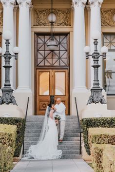 a bride and groom standing on the steps of a building