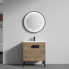 a bathroom vanity with a round mirror on the wall above it and a black metal faucet