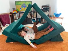 two children laying on top of an inflatable triangle shaped chair with their arms around each other