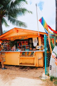 a yellow food stand with surfboards and palm trees in the backgroung