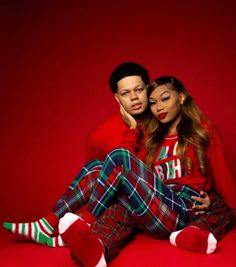 a man and woman sitting on top of each other wearing matching plaid pajamas with red socks