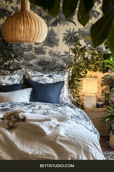 a bed with blue and white comforter in front of a palm tree wallpaper