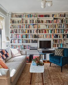 a living room filled with furniture and bookshelves full of books on the wall