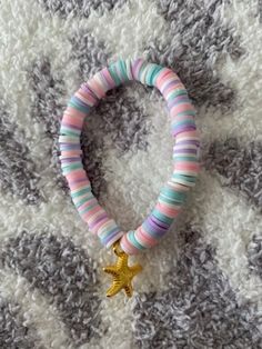 a bracelet with a gold star on it sitting on top of a white and gray blanket