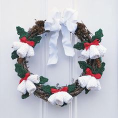 a christmas wreath hanging on the front door with white bows and pine cones, decorated with crochet