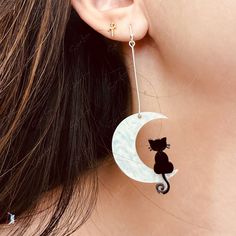 Elevate your style with these one-of-a-kind dangle drop earrings crafted from a stunning black cat on moon resin charm and solid 925 sterling silver. Whether you're adding them to your fine jewelry collection or gifting them to a loved one, these earrings are the perfect blend of elegance and meaning. Make a statement with these unique and symbolic earrings. Materials: resin charm, 925 sterling silver Dimensions: 3 x 1 in Jewelry Care: See more information about how to care for your jewelry here Symbolic Moon Shaped Sterling Silver Earrings, Symbolic Moon-shaped Earrings For Gift, Elegant Moon-shaped Metal Earrings, Moon-shaped Sterling Silver Earrings, Symbolic Moon-shaped Sterling Silver Earrings, Cat On Moon, Moon Resin, Resin Charms, Earring Crafts