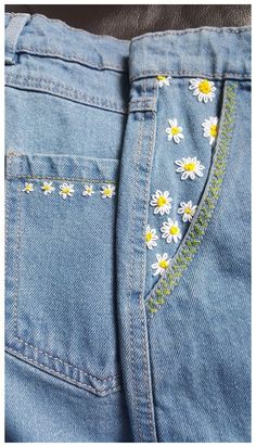 a pair of jeans with daisies embroidered on them