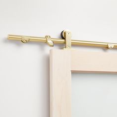 a close up of a wooden frame with a metal bar on the side and a white wall behind it