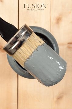 a paint brush is being used to paint a wood paneled wall with the words fusion mineral paint on it