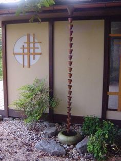 there is a small tree in front of the building with rocks and plants around it