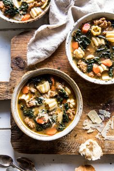 two bowls of pasta and vegetable soup on a wooden table