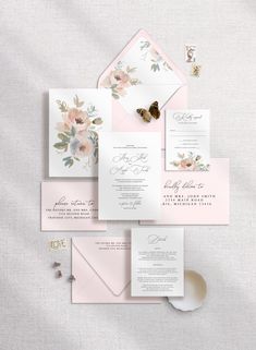 the wedding stationery is laid out on top of each other, including pink and white flowers