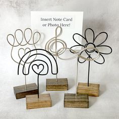 three metal flower sculptures on wooden bases with a sign in the background that says insert note card or photo here