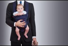 a man in a suit holding a baby while wearing a tie and carrying a briefcase