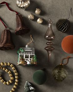 various christmas ornaments are arranged on a gray surface with red ribbon and other decorations around them