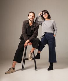 two people sitting on stools posing for the camera