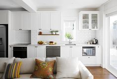 a white couch sitting next to a kitchen with lots of counter space and cabinets in it