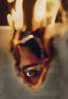 the reflection of a woman's face in a mirror with candles behind her,