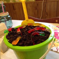 a green bucket filled with dirt and gummy bears on top of a white table