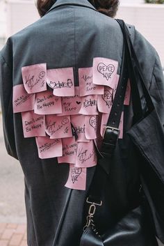 the back of a woman's jacket covered in pink sticky notes