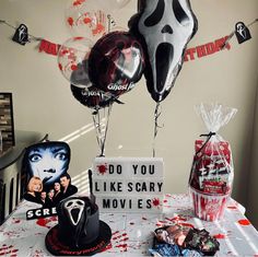 a table topped with balloons and other items next to a sign that says do you like scary movies?