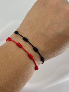 a person wearing a red and black string bracelet