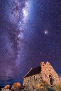 the milky shines brightly above an old church on top of a rocky outcropping