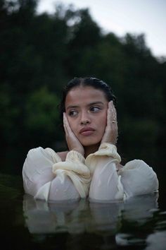 a woman with her hands on her face in the water, looking at the camera