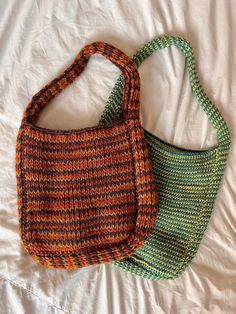 two purses sitting on top of a bed next to each other in different colors