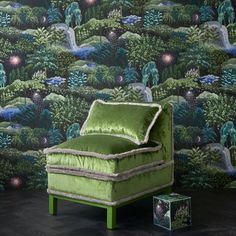 a green chair sitting in front of a wallpapered background with trees and bushes