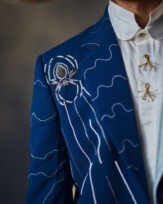 The Floating Spider | Jatin Malik Introducing our Blazer Set inspired by Dali’s infamous painting - "Spider of the Evening 1940". Delicately embroidered with ivory cross and chain stitches, this ensemble weaves a tale of mystery and sophistication. Its unique patchwork, contrasting against its deep base color, echoes the enigmatic charm of the night, inviting you to embrace a world of unparalleled elegance. Paired with a white shirt and matching tapered trousers, this ensemble offers a refined and polished look that is perfect for making a statement at any formal occasion or special event. Step into the realm of art and elegance with this captivating ensemble, designed to capture attention and leave a lasting impression. Included in purchase: Blazer, Shirt, Trousers Product Specification C Spider Embroidery, Button Knot, Jatin Malik, Embellished Blazer, Blouse Yoke, Knit Embroidery, Embroidery Neckline, Embroidered Blazer, Personal Shopping Service