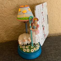 a figurine on a table with a lamp and book in front of it