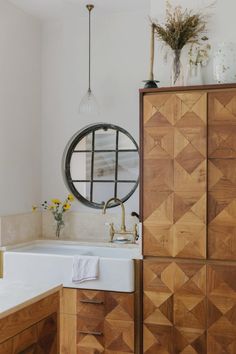 a kitchen with a sink, cabinets and a round mirror above the sink in front of it