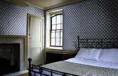 a bedroom with a bed, fireplace and wall papered in shades of blue on the walls