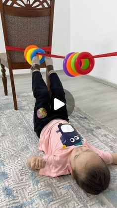 a toddler laying on the floor playing with colorful toys and balancing it over his head