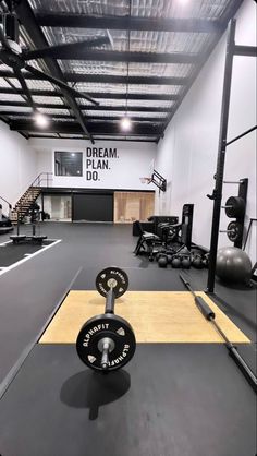 an empty gym with weight plates and barbells on the floor in front of a sign that says dream plan do