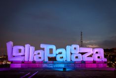 the large letters are lit up in pink and blue colors, with buildings in the background