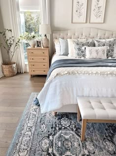 a bedroom with a large bed and blue rugs on the floor next to a window