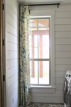 a window in the corner of a room with a patterned rug on the floor next to it