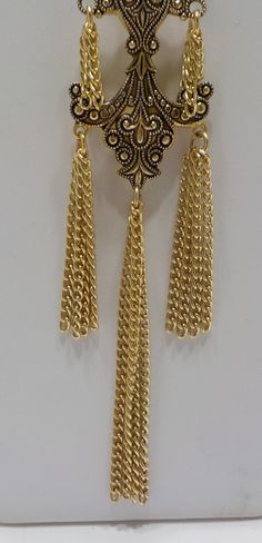 "Vintage gold tone dangling necklace resembling Damascene or Toledoware. 30\" gold tone pullover chain attached to a pendant measuring 1 1/4\" x 3 1/2\" including tassels. Gorgeous and in excellent condition." Gold Long Necklace With Adjustable Chain For Jewelry Making, Metal Dangle Chain Necklace Costume Jewelry, Elegant Gold Chain Necklace With Dangling Charms, Metal Long Dangle Necklace As A Gift, Metal Dangle Long Necklace For Gift, Dangle Long Metal Necklace As Gift, Dangle Long Necklace As Gift, Gold Necklaces With Dangling Charms, Adjustable Gold Brass Long Necklace