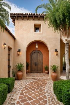 the entrance to an adobe style home with potted plants and large pots on either side