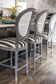 four chairs are lined up in front of a kitchen island with black and white striped cushions