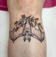 a bat tattoo on the ankle with leaves