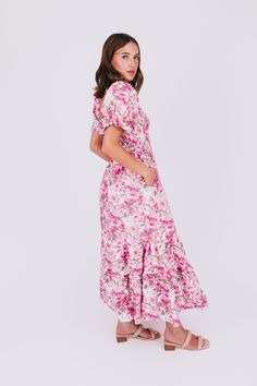 Stay light-hearted and lovely in the Rosy Outlook Dress. This tiered maxi length dress boasts a playful sweetheart neckline, puff sleeves, and a flirty ruffle on the shoulders. The floral pattern in shades of pink and green on a white background will have you feeling positively blooming. Details Smocked bodice Tiered Floral pattern with shades of pink and green on a white background Slight puff sleeve with elastic Ruffle on shoulders of neckline Sweetheart neckline Maxi length Lined on chest dow Spring Pink V-neck Tiered Dress, Pink Tiered Dress For Garden Party, Pink Flowy Tiered Dress For Garden Party, Spring Pink Tiered Dress For Garden Party, Pink Tiered Ruffle Dress For Garden Party, Feminine Flutter Sleeve Maxi Dress For Garden Party, Pink Tiered Skirt Midi Dress For Garden Party, Pink Tiered Dress For Spring Garden Party, Feminine Maxi Dress With Flutter Sleeve For Garden Party